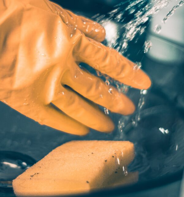 Gloved hand with sponge and running water to illustrate impact washing