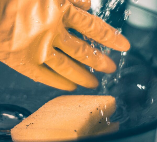 Gloved hand with sponge and running water to illustrate impact washing
